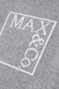 Grå strikket stoff med et hvitt rektangulært logo som har teksten "MAX & 8" i en moderne skrifttype. Teksturen ser myk og tett ut.