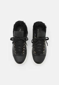 Czarne skórzane trampki z podszyciem z faux futra, z czarnymi sznurówkami i złotymi oczkami. Białe gumowe podeszwy i elegancki, zaokrąglony kształt.