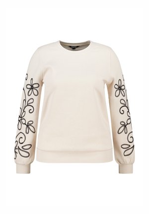Sweatshirt crème à manches longues avec des broderies florales noires sur chaque manche et des poignets côtelés. Texture lisse avec un col arrondi.