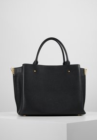 Czarna skórzana torba na ramię o teksturowanej powierzchni, z dwiema mocnymi uchwytami, złotymi akcentami i sztywną formą. Minimalistyczny design bez widocznych logo.