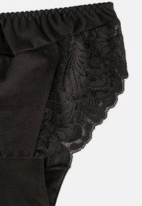 Culotte noire en tissu lisse avec une bordure en dentelle au dos, présentant un motif floral et un bord festonné. Taille élastique.