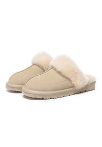 Beige Hausschuhe zum Hineinschlüpfen mit einem weichen, flauschigen Fellbesatz und einem Obermaterial aus Wildleder. Die Laufsohle besteht aus einem stabilen, strukturierten Gummi für Rutschfestigkeit und Langlebigkeit.