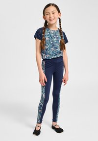 Completo sportivo navy con top a fantasia floreale e leggings a tinta unita con pannelli laterali floreali. Materiale morbido e elasticizzato; design aderente.