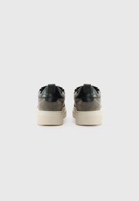 Par med låga sneakers med grå mockakroppar, svarta läderhæl-accenter och kraftiga off-white gummisulor, sedd bakifrån.