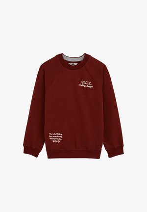 Bordo pulover z okroglim izrezom in raglan rokavi. Na sprednji strani in na manšetah je bel izvezen napis. Mehka tekstura tkanine.