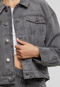 Grå denimjacka med krage, knappstängning fram, två bröstfickor och uppvikta ärmar, med detaljer i silverfärgade metall.