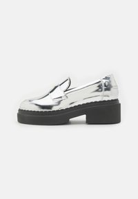 Scarpe slip-on in metallo argentato con suola piattaforma nera chunky, cuciture decorative e punta arrotondata. Design senza soluzione di continuità con accentuazioni minime.
