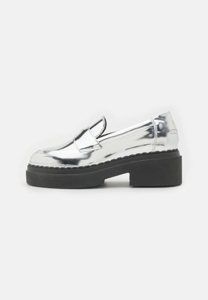 Silver metallic slip-on shoes with chunky black platform sole, decorative stitching, and a rounded toe. Seamless design with minimal accents.