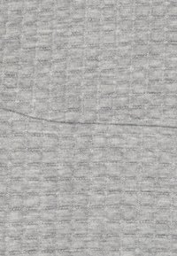 Grått texturerat tyg med ett rutnätsmönster och subtilt upphöjda detaljer, som ger en mjuk och hållbar yta.