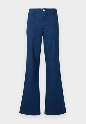 Donkerblauwe, uitlopende denim jeans met hoge taille, voorzakken met klep en knoopsluiting, afgebeeld op een witte achtergrond.