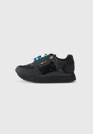 Zapatilla negra Replay con paneles texturizados y brillantes, suela gruesa y etiquetas de marca multicolores en los cordones negros, logo lateral visible.