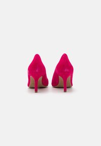 Chaussures à talons hauts en suède fuchsia, avec une pointe effilée et un talon mince. La texture est douce et veloutée, mettant en valeur une surface lisse.