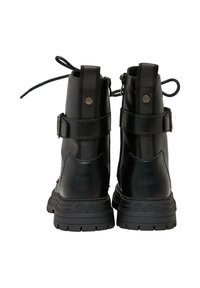 Botas de combate de cuero negro con suelas de goma gruesas, tiradores traseros, correas ajustables y cremalleras laterales, vistas desde atrás.
