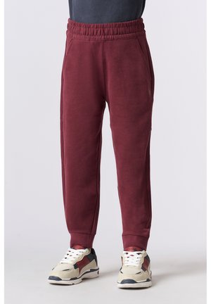 Pantaloni jogger in fleece bordeaux con cintura elastica, tasche laterali e polsini affusolati. Indossati con sneakers beige e navy.