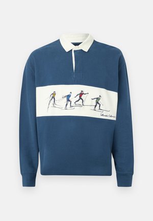 Plava ragbi majica dugih rukava s bijelim ovratnikom i bijelom horizontalnom prugom s prikazom skijaša u šarenim odijelima i tekstom "Telluride Colorado".