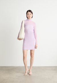 Lavender long-sleeve dress with a fitted silhouette, sheer texture, and subtle pattern. Paired with a cream shoulder bag and strappy heels.