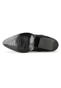 Suela de zapato de cuero negro con forma puntiaguda, texturizada con estrías y surcos, y con una sección de tacón lisa.