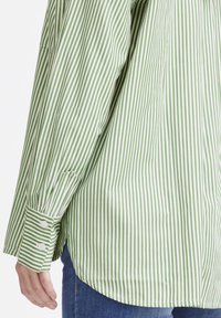 Green and white striped long-sleeve shirt. Features button cuffs and a curved hem, made from a lightweight, smooth fabric.