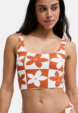 Top crop z pomarańczowo-białym kwiatowym wzorem w kratkę. Wykonany z teksturowanej tkaniny, z szerokimi ramiączkami i kwadratowym dekoltem.