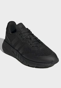 Melnas sporta kurpes ar auduma augšdaļu, trīs joslu dizainu, strukturētu melnu gumijas zoli un mīkstu apmalei atbalstam.