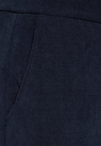 Marine corduroy stof met verticale ribbelstructuur, voorzien van een zijzak en een elastische tailleband, geschikt voor casual wear.