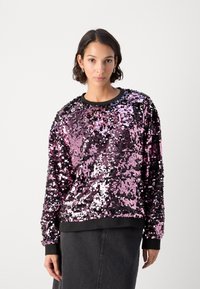 Sudadera de lentejuelas en rosa y negro con un cuello redondo, mangas largas y puños acanalados en el dobladillo y las muñecas, creando una superficie texturizada.
