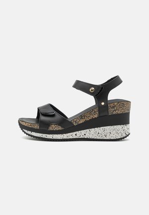 Black wedge sandals with cork detailing, adjustable straps, textured sole, and speckled white outsole. Features gold hardware accents.