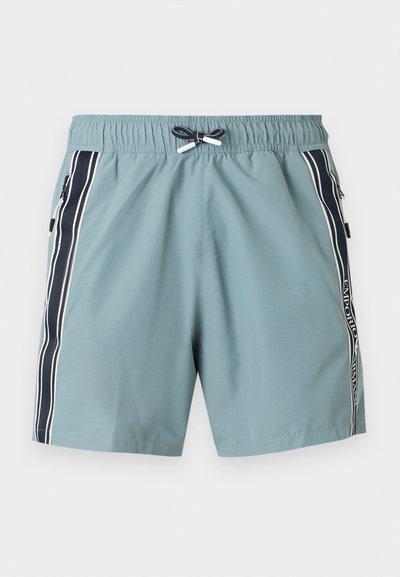 Ανοιχτό τιρκουάζ μαγιό σορτς με ελαστική μέση, μαύρες και λευκές πλευρικές ρίγες, τσέπες με φερμουάρ και κορδόνι στη μέση μπροστά.