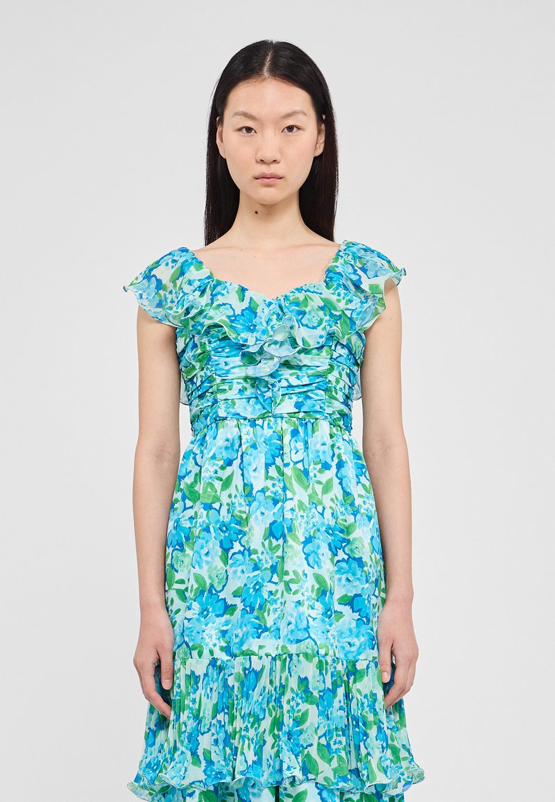 Robe florale bleue et verte avec des manches volantées, un corsage ajusté et une jupe évasée ornée de volants superposés à l'ourlet. Texture de tissu douce.