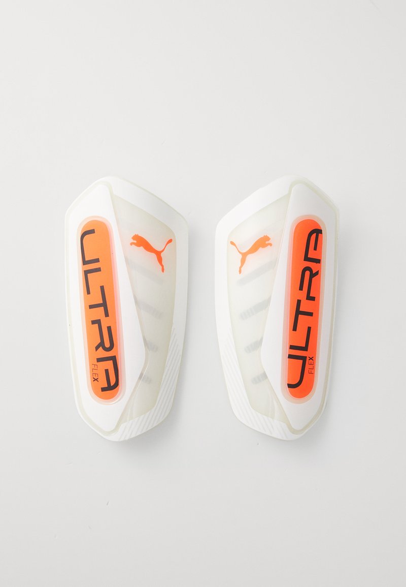 Puma Ultra Flex leggbeskyttere i hvit og oransje, med en glatt skalldesign, elastiske bånd og "ULTRA"-merke på forsiden.