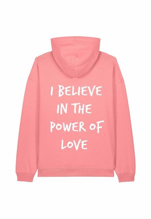 Haut à capuche rose avec une poche kangourou et un cordon de serrage à la capuche. Comprend un texte blanc qui indique "JE CROIS EN LE POUVOIR DE L'AMOUR" au dos.