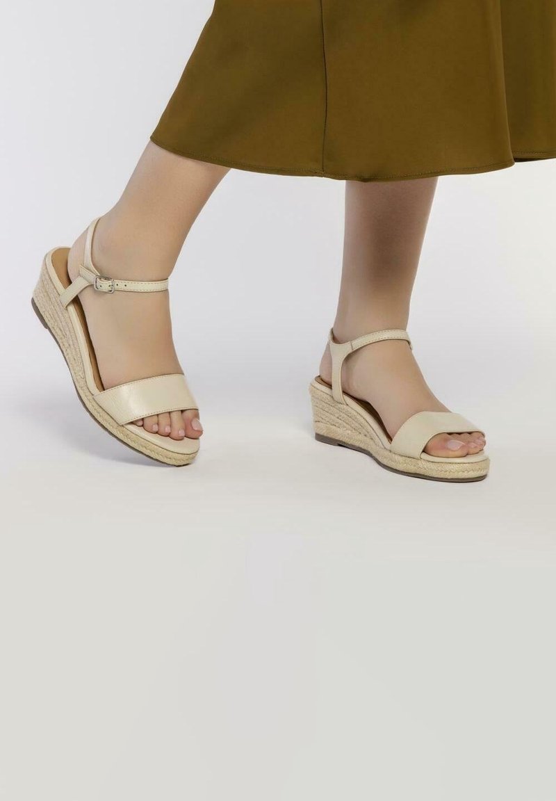 Sandales compensées beiges avec une finition en cuir lisse, dotées de deux larges lanières, d'une bride de cheville réglable et d'une semelle en jute tissée.