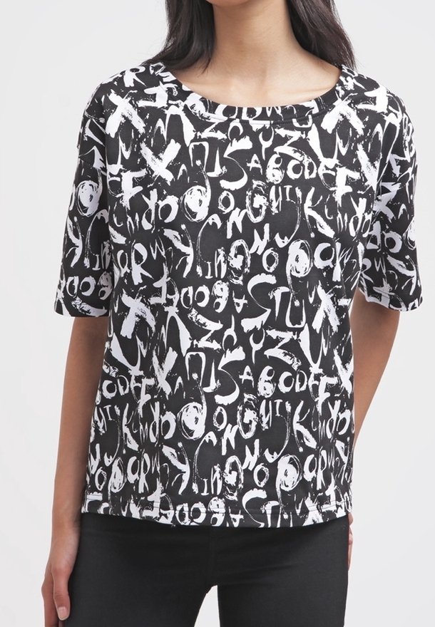 T-shirt nera a maniche corte con un motivo testuale astratto bianco, scollo tondo e vestibilità rilassata. Il tessuto appare liscio e leggero.