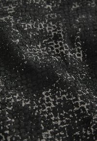Svart tyg med en texturerad yta, prytt med ett spritt grått mönster. Designen verkar intrikat och vävd, vilket framhäver djup.