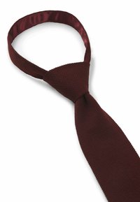 Burgundy-texturoitu solmio, jossa on tuntuva neulominen ja jonka kaulassa näkyy sileä satiinivuori sekä kapeneva pääty.