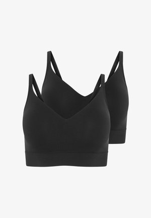 Czarny bralet z dekoltem w serek w połączeniu z białymi szortami. Modelka ma na sobie lekką koszulę w paski na guziki, o miękkiej teksturze i luźnym kroju.