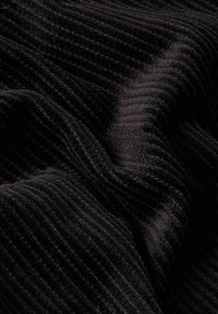 Zwarte ribbelsstof met een gestructureerd oppervlak, dat zachte, dichte vezels toont die subtiele golfpatronen en diepte creëren.