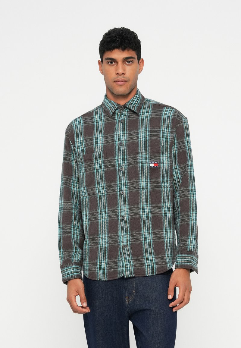 Skjorte i ternet flannel i brun og turkis, med krave der kan knappes ned, en lomme på brystet og et lille logo på brystet. Blød tekstur.