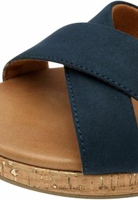 Sandalia cruzada de color azul marino con una plantilla de imitación cuero en tono marrón y suela con textura de corcho. Presenta detalles de costura en las correas.
