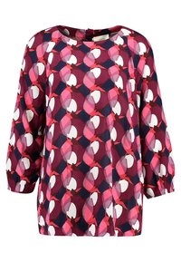 Haut à manches longues avec un col rond, présentant un motif géométrique en rose, bleu marine et blanc. Confectionné en tissu léger et lisse.