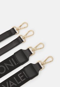 Schwarze Taschenträger mit goldfarbenen Metallclips, Lederelementen und einer strukturierten Oberfläche mit geprägtem Schriftzug.
