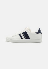 Sneaker in pelle bianca con accenti blu navy, caratterizzato da due strisce orizzontali e dettagli di marca, suola piatta e punta rotonda.