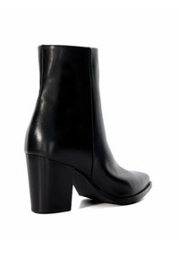 Bottine en cuir noir avec un bout carré et un talon épais. Texture lisse, design ajusté et accents de couture minimalistes.