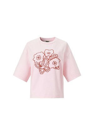T-shirt rose clair à manches courtes avec une bordure brodée rouge représentant trois fleurs et feuilles sur le devant.