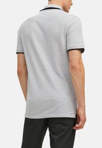 Grijze polo met een gestructureerd oppervlak, voorzien van een contrasterende zwarte kraag en mouwafwerking, korte mouwen en een rechte zoom.