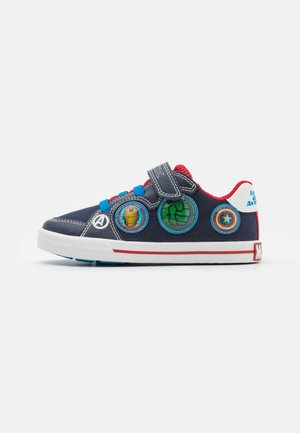 Baskets en toile bleu marine avec des accents rouges, une sangle Velcro et des patches circulaires de personnages (Iron Man, Hulk, Captain America) sur le côté.