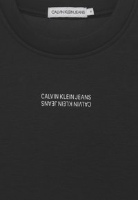 Czarny bawełniany t-shirt z okrągłym dekoltem. Posiada odwrócone białe logo "CALVIN KLEIN JEANS" nadrukowane na klatce piersiowej.