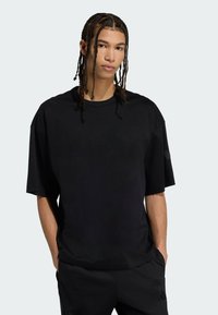 Sort oversized t-shirt lavet af et glat, let stof. Har korte ærmer og en rund halsudskæring, designet med en afslappet pasform.