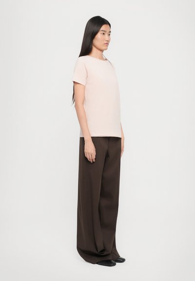 Light pink t-shirt with short sleeves, paired with dark brown wide-leg trousers. Smooth fabric with a relaxed fit and minimal design.