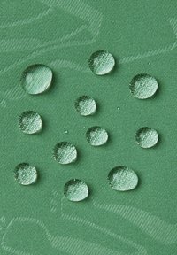 Zielona, teksturowana tkanina z wieloma kroplami wody o różnych rozmiarach, pokazująca wyraźne odbicia i okrągłe kształty, podkreślająca właściwości wodoodporne.